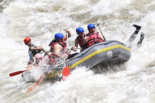 River rafting guide navigates clients through rough waters